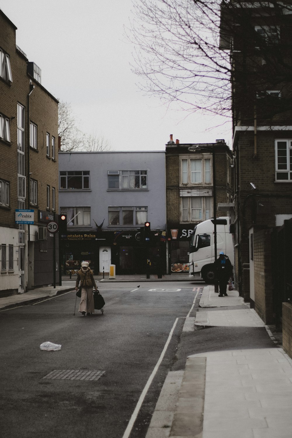 a woman walking down a street next to tall buildings