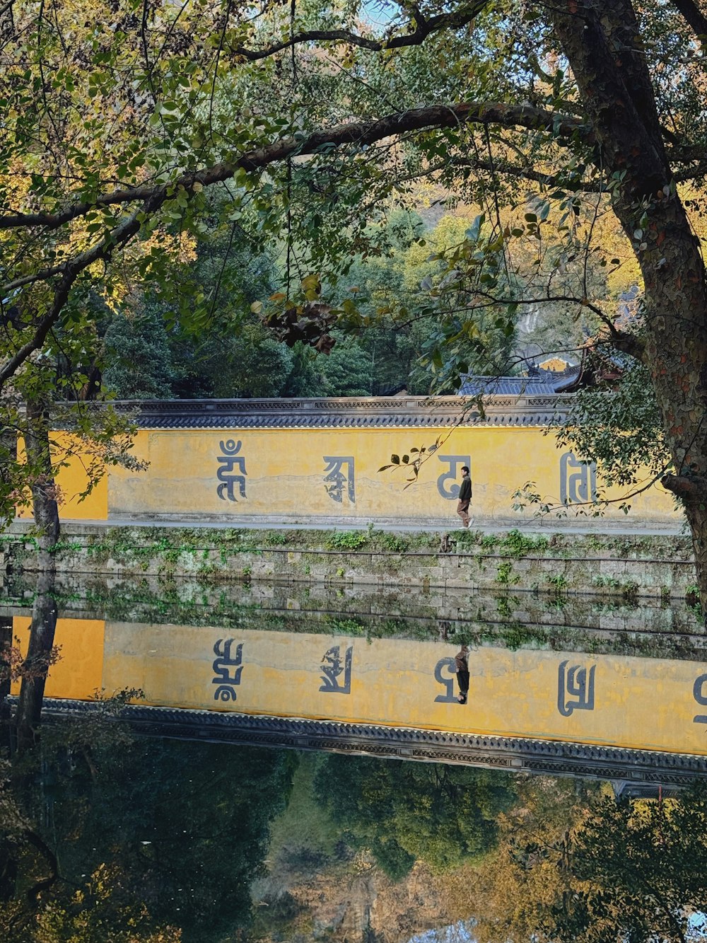 eine gelbe Brücke über ein von Bäumen umgebenes Gewässer