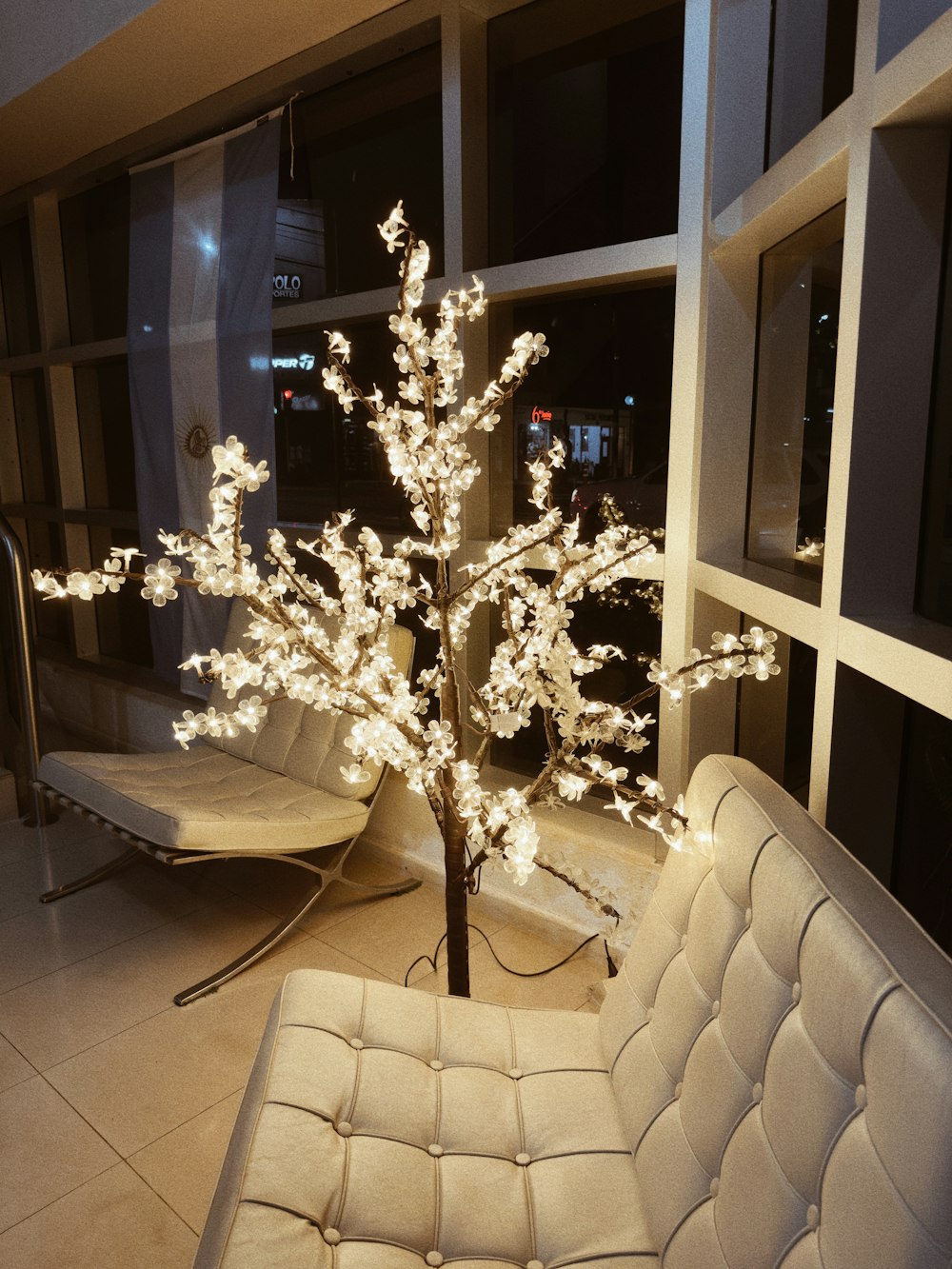 a white couch sitting next to a tree with white lights