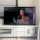 Happy woman enjoying a flat-screen TV inside a bright motel room.