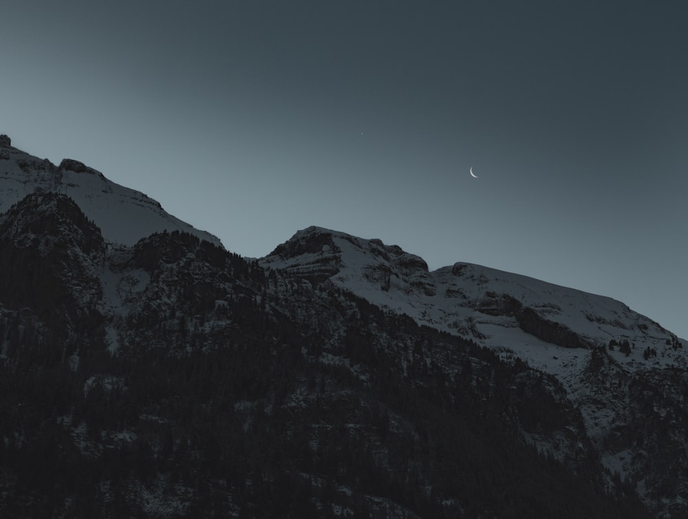 a mountain with a half moon in the sky