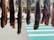 Several pieces of meat are hanging vertically in a row, suspended above a sidewalk with a striped crosswalk in the background. They appear to be drying or curing in the open air, and there is a mix of sunlight and shadow on the scene.