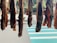 Several pieces of meat are hanging vertically in a row, suspended above a sidewalk with a striped crosswalk in the background. They appear to be drying or curing in the open air, and there is a mix of sunlight and shadow on the scene.