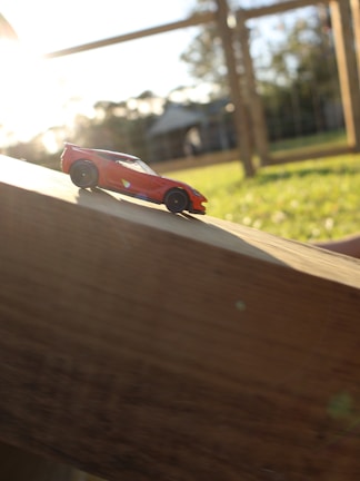 A vibrant red wooden soapbox car on a sunny hill.