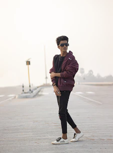 A young person wearing a full streetwear outfit walking confidently through a city street at dusk.