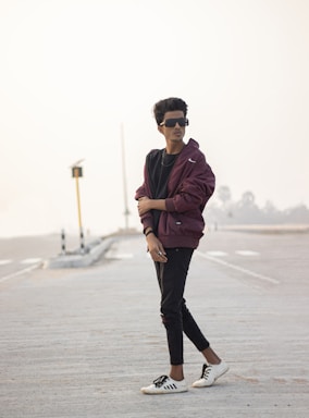 A young person wearing a sleek urban jacket walking confidently through a city street at dusk.