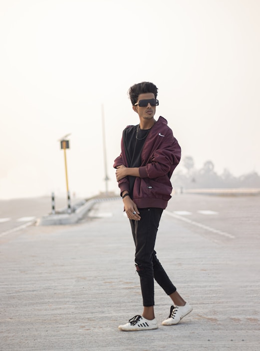 A young person wearing a sleek urban jacket walking confidently through a city street at dusk.