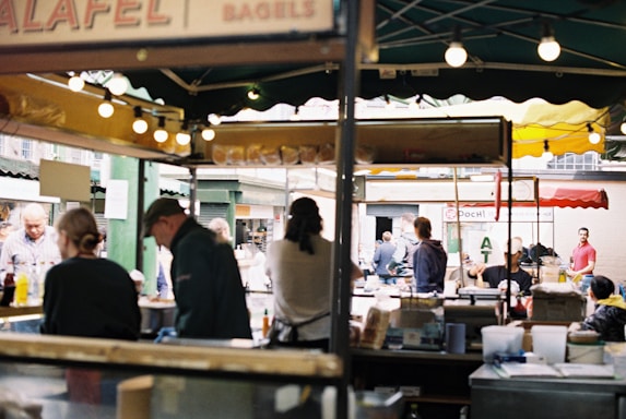 A vibrant market scene with food stalls and people enjoying meals.