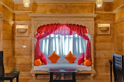 A peaceful seating area with traditional decor near a window framing Balaji temple in the distance.