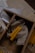 A wooden box divided into sections contains several small hand-rolled yellow beeswax candles, some resting on a piece of natural-colored fabric. Papers and possibly tags are scattered nearby.