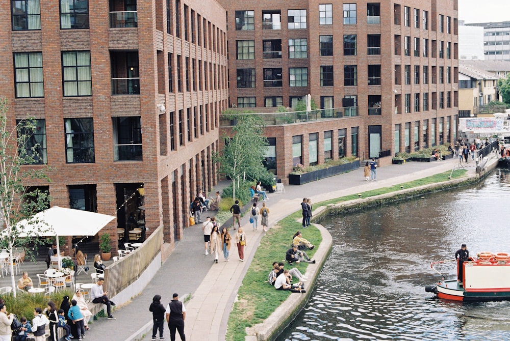 a group of people walking down a sidewalk next to a river