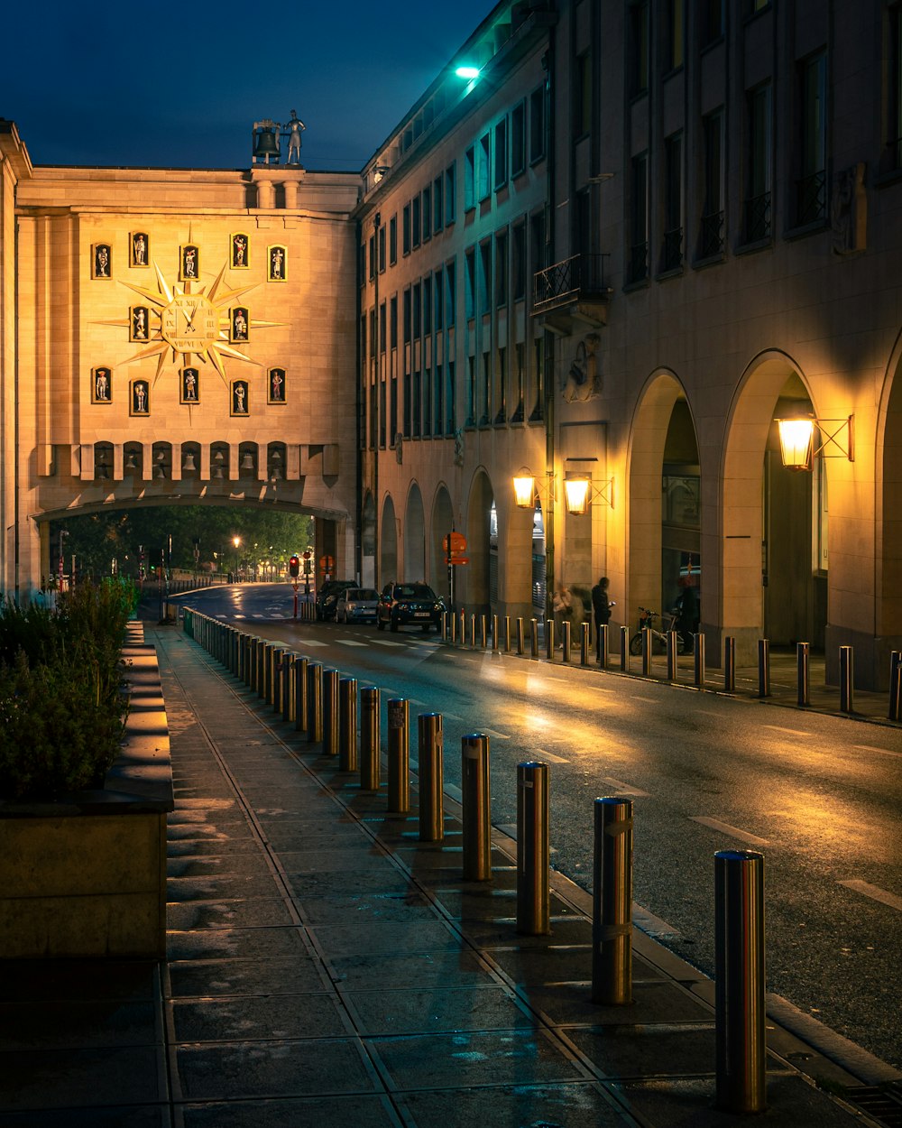 una calle de la ciudad por la noche con un gran edificio al fondo