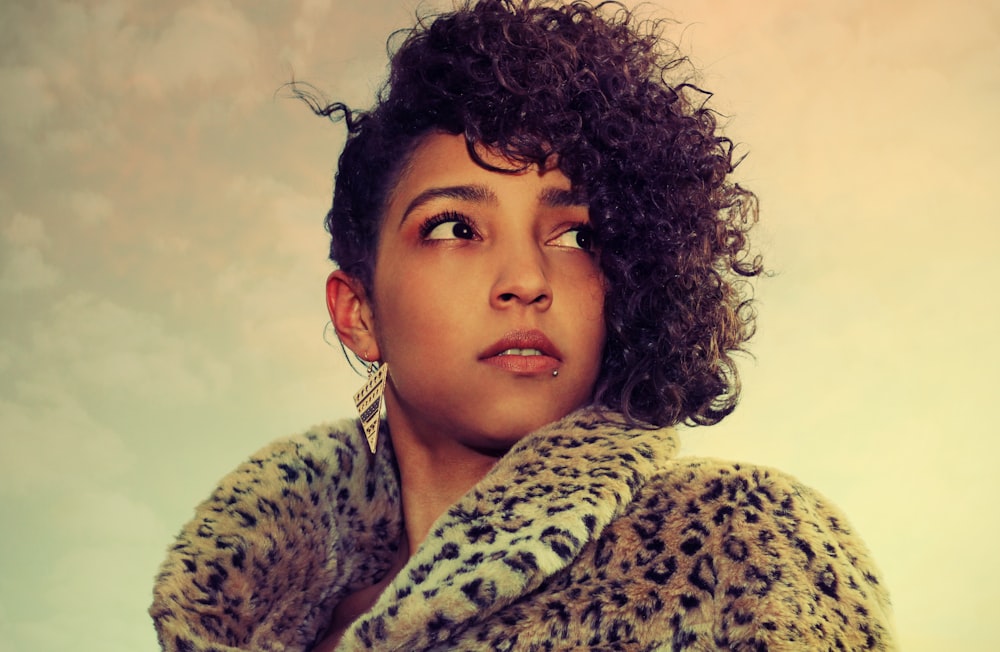 a woman with curly hair wearing a leopard coat