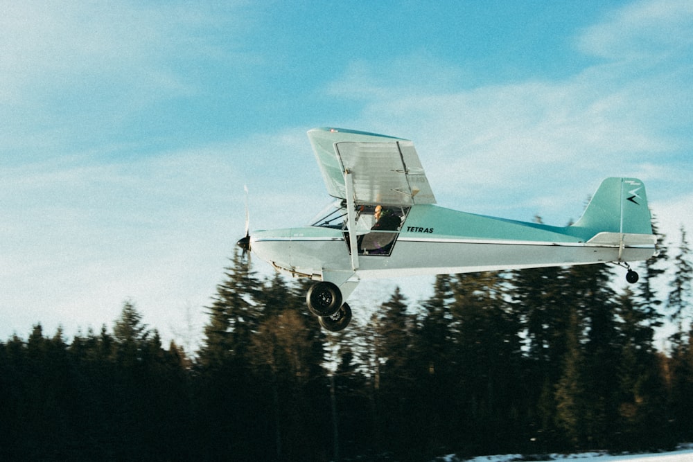 a small airplane flying over a snow covered field