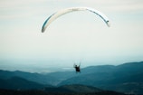 A beginner pilot launching a paraglider on a clear sunny day at a green hillside