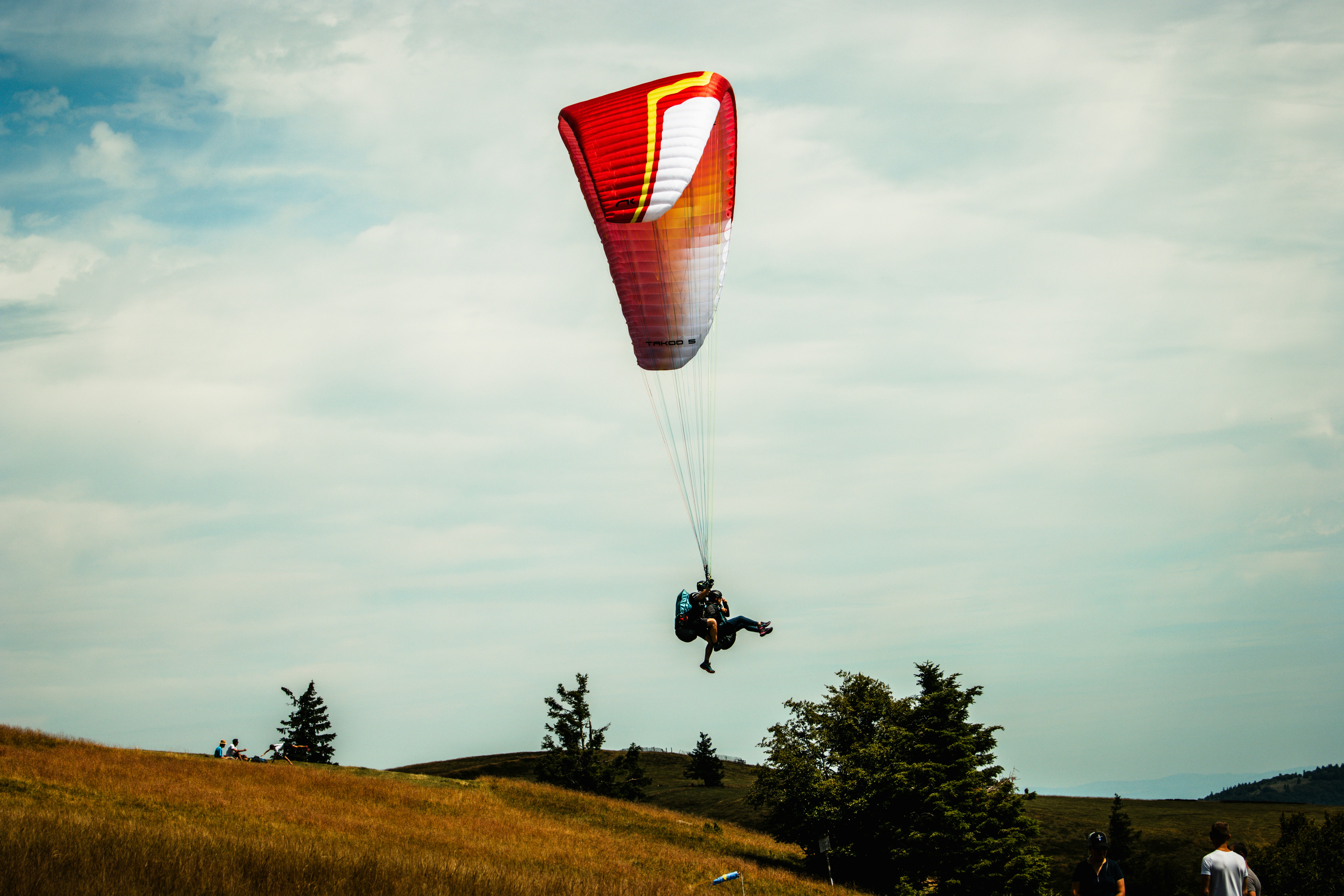 a person is parasailing over a grassy hill