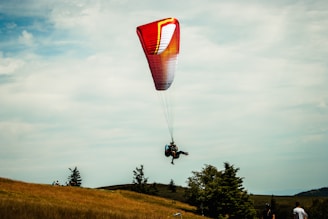a person is parasailing over a grassy hill