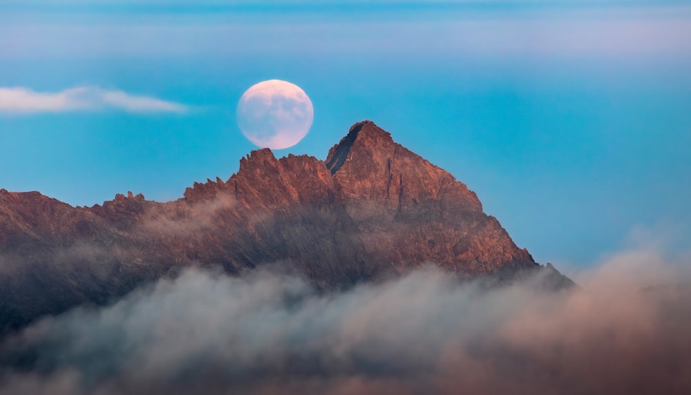 a full moon rising over a mountain range