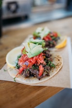 Close-up of a sizzling taco being prepared with fresh ingredients on a rustic wooden board.