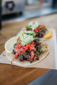 Close-up of a colorful taco with fresh ingredients on a rustic wooden table.