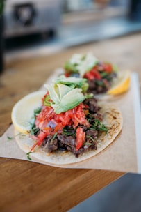 Close-up of a sizzling taco being prepared with fresh ingredients on a rustic wooden board.