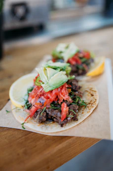 Close-up of a freshly made classic taco with vibrant toppings on a rustic wooden table.