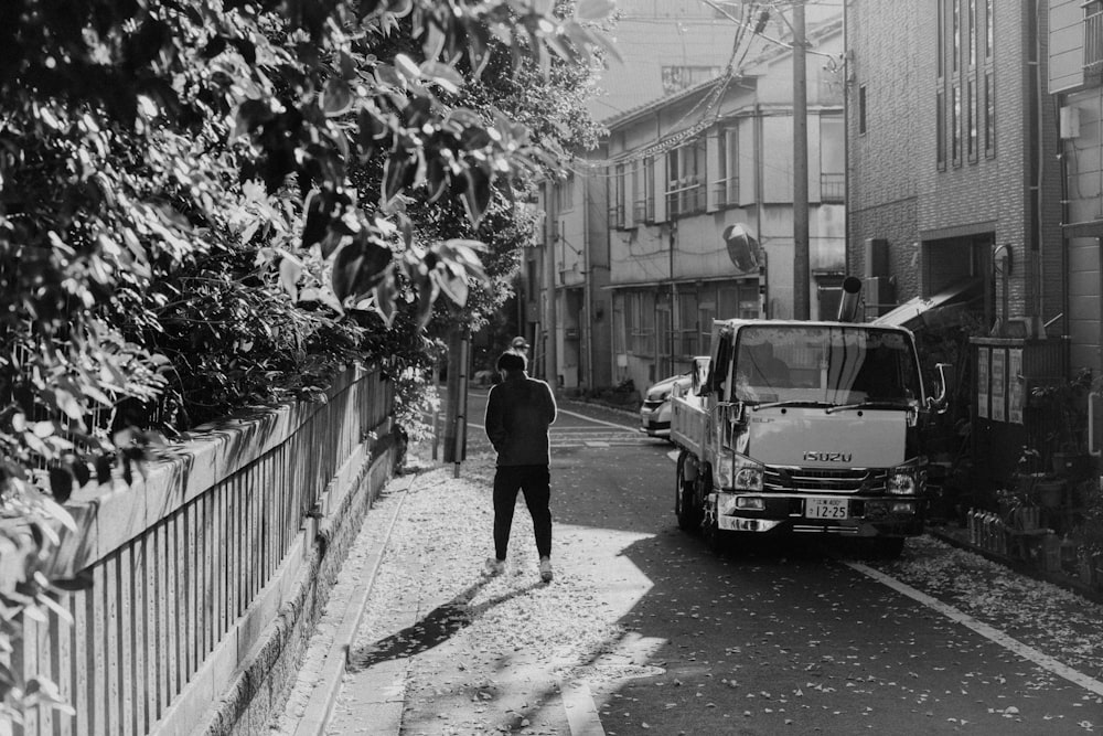 a black and white photo of a man standing next to a truck