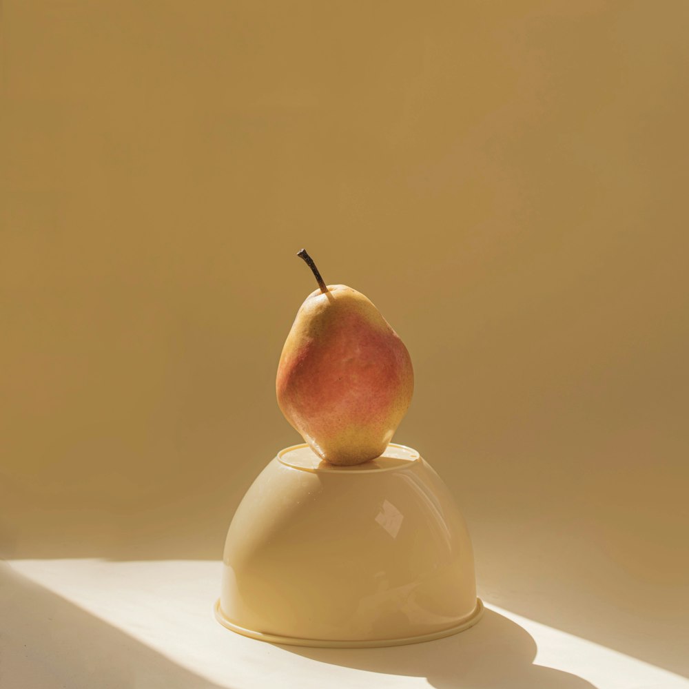 an apple sitting on top of a white bowl