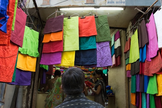 A colorful display of silk sarees and readymade garments beautifully arranged in a traditional South Indian shop.