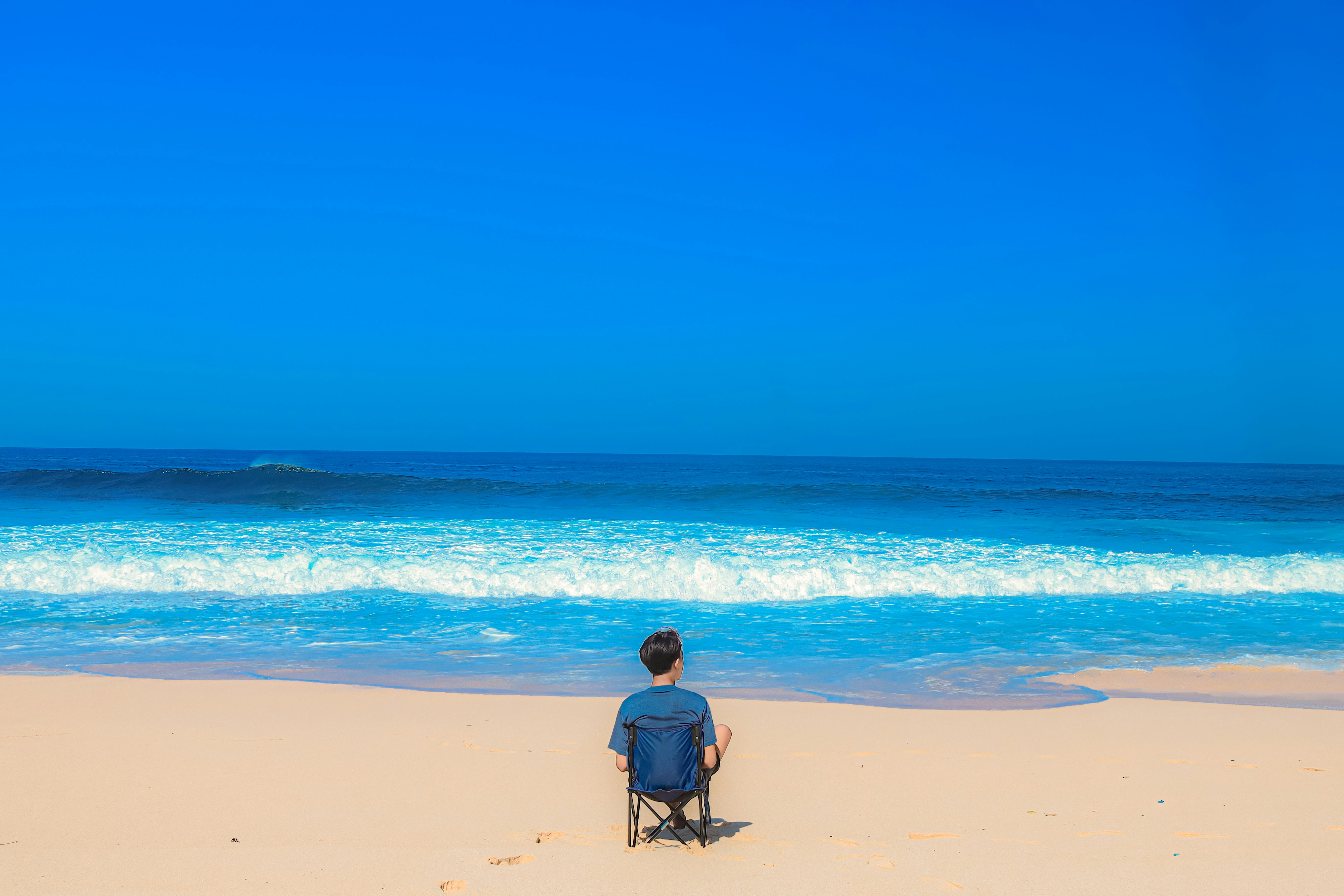un homme assis sur une chaise sur la plage