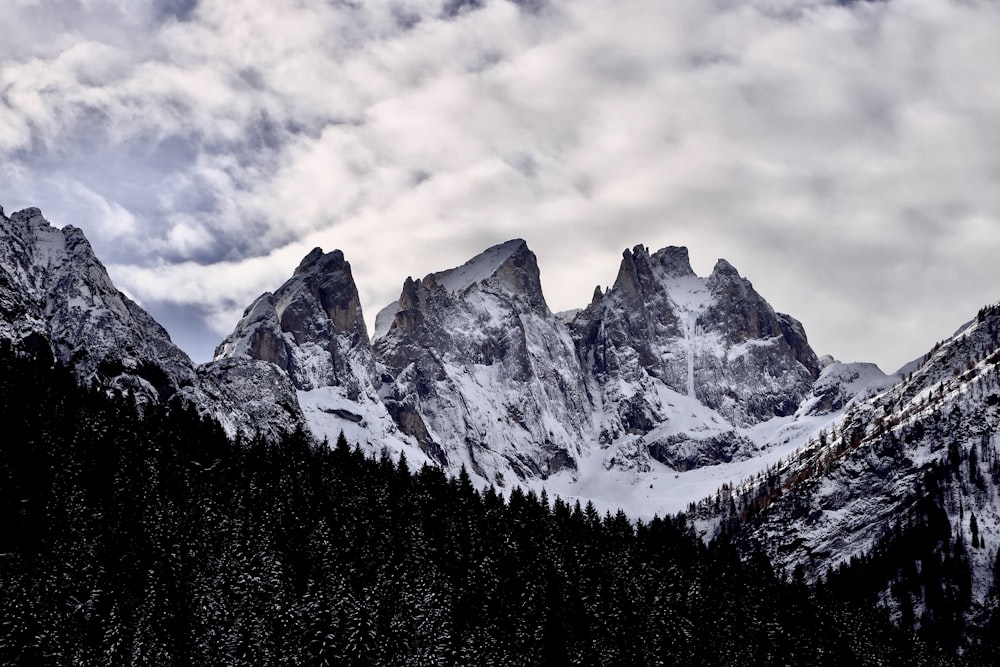 a snow covered mountain range under a cloudy sky