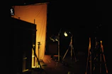 A behind-the-scenes shot of a video shoot with lighting equipment and a director guiding the scene.