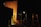 The scene appears to be staged in a dark environment with professional lighting equipment aimed at a large, orange-tinted diffusion panel or backdrop. Various tripods and stands are visible, along with some cables on the floor.