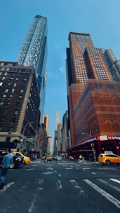 A bustling New York City street with skyscrapers and yellow taxis under a clear sky.