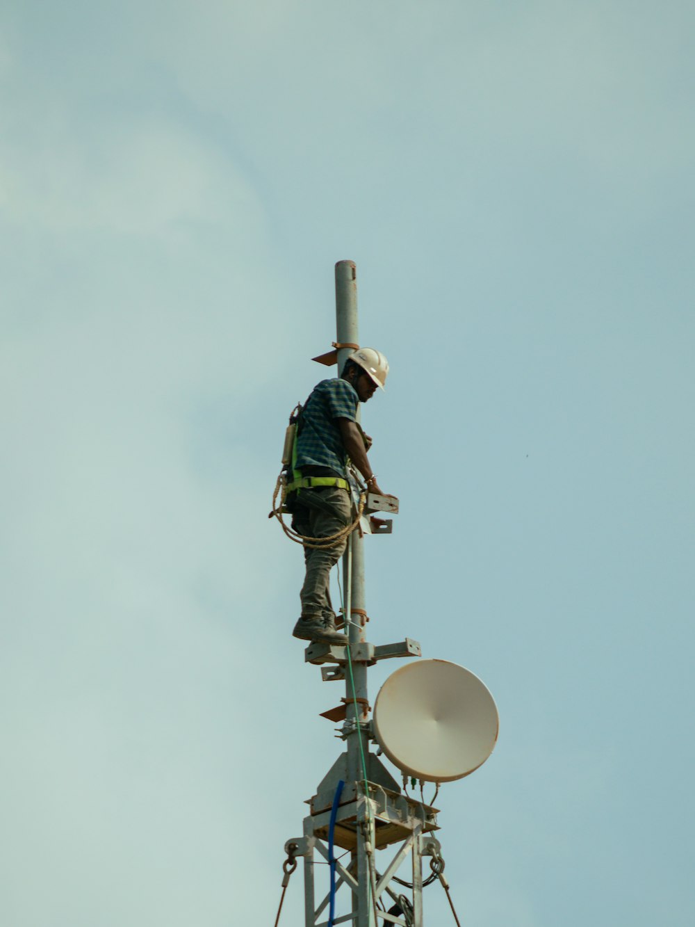 a man standing on top of a tower next to a satellite dish