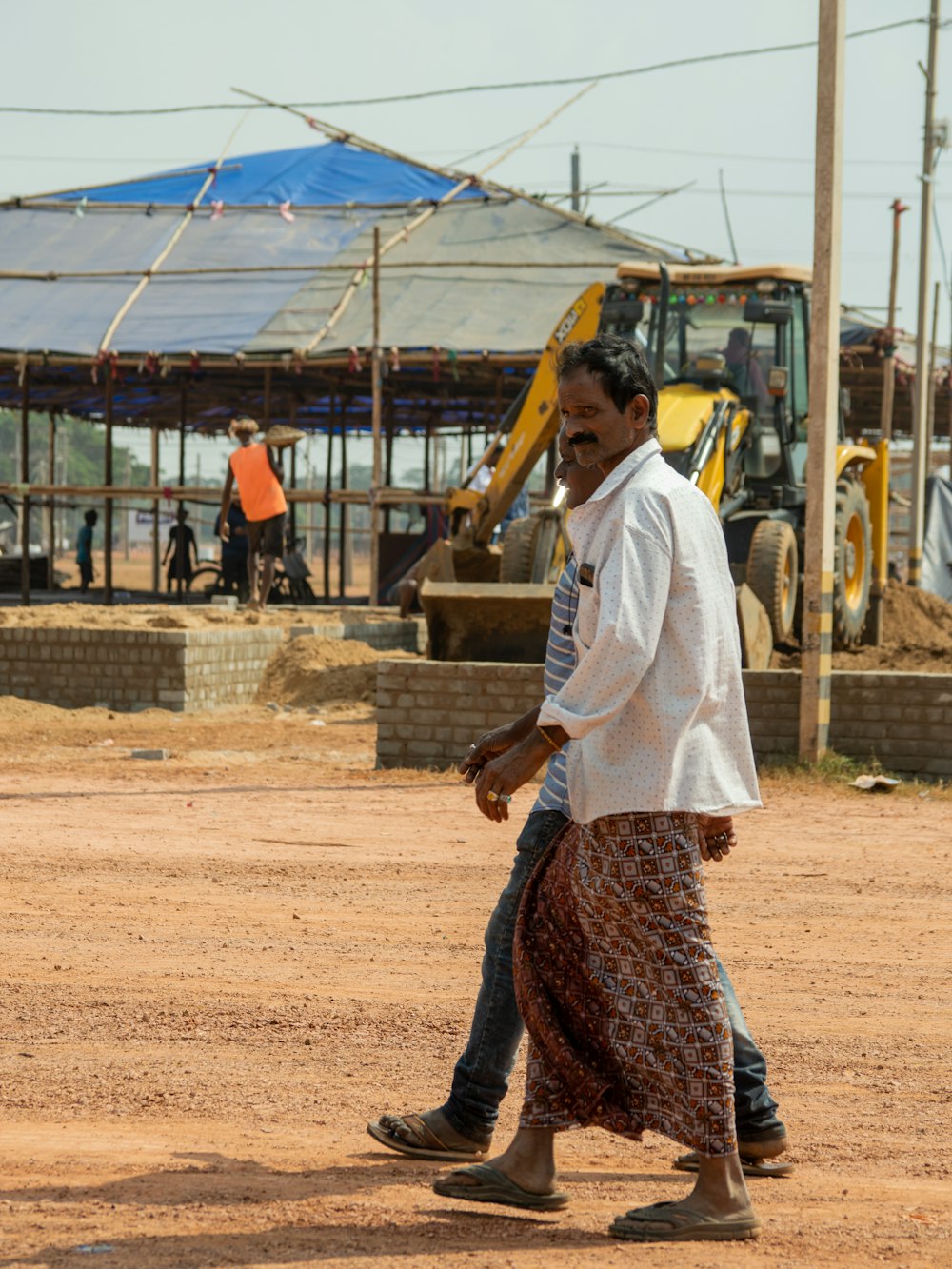a man walking across a dirt field next to a construction site