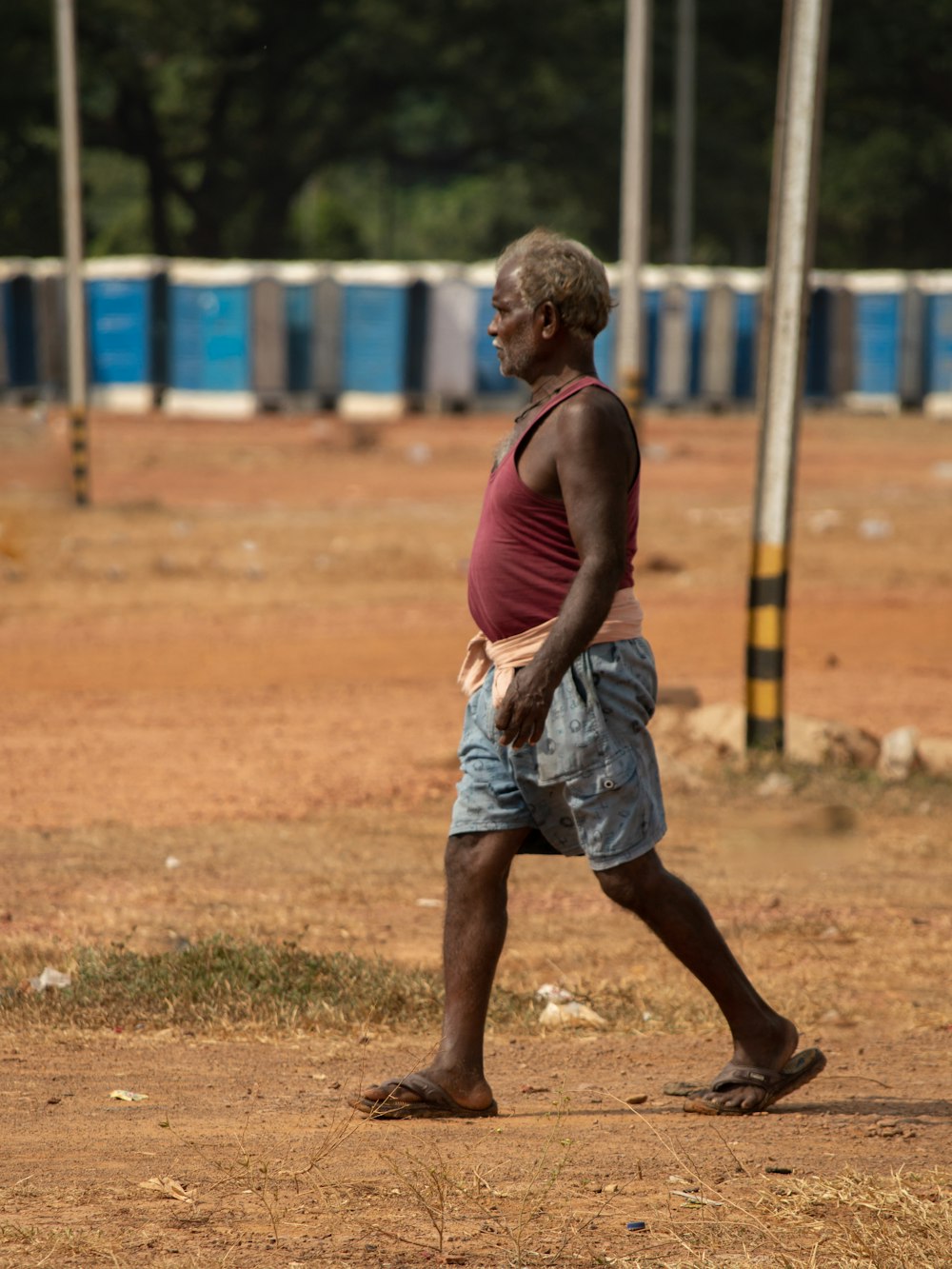 a man walking across a dirt field holding a frisbee