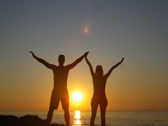 a couple of people standing on top of a beach