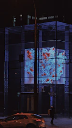 a car driving past a tall building at night
