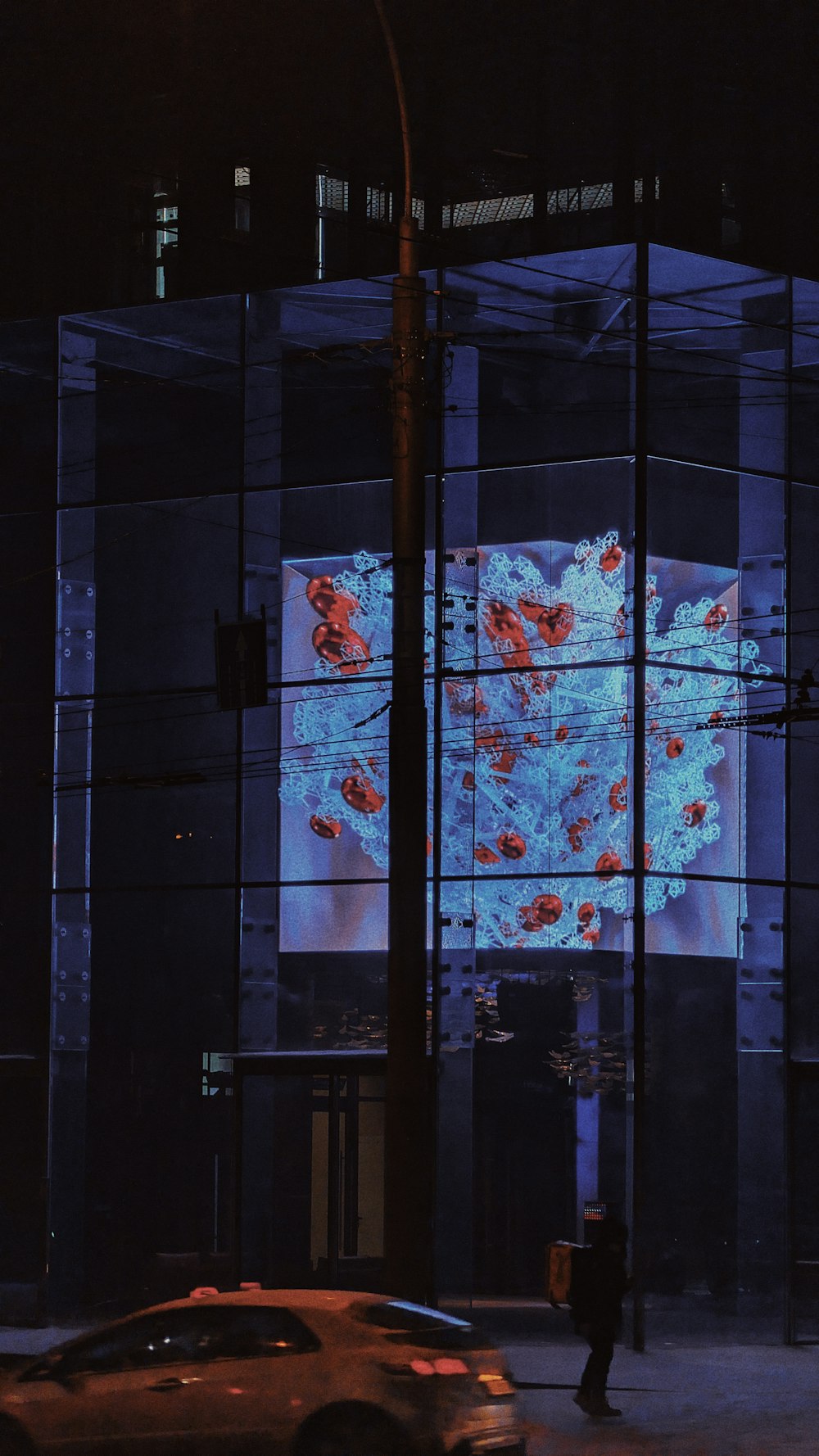 a car driving past a tall building at night