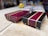 Two rectangular wooden blocks rest on a light-colored surface. The blocks have a striking design with alternating strips of dark brown, deep purple, and light tan wood. The wood appears polished and intricately crafted, with smooth, shiny surfaces and beveled edges.