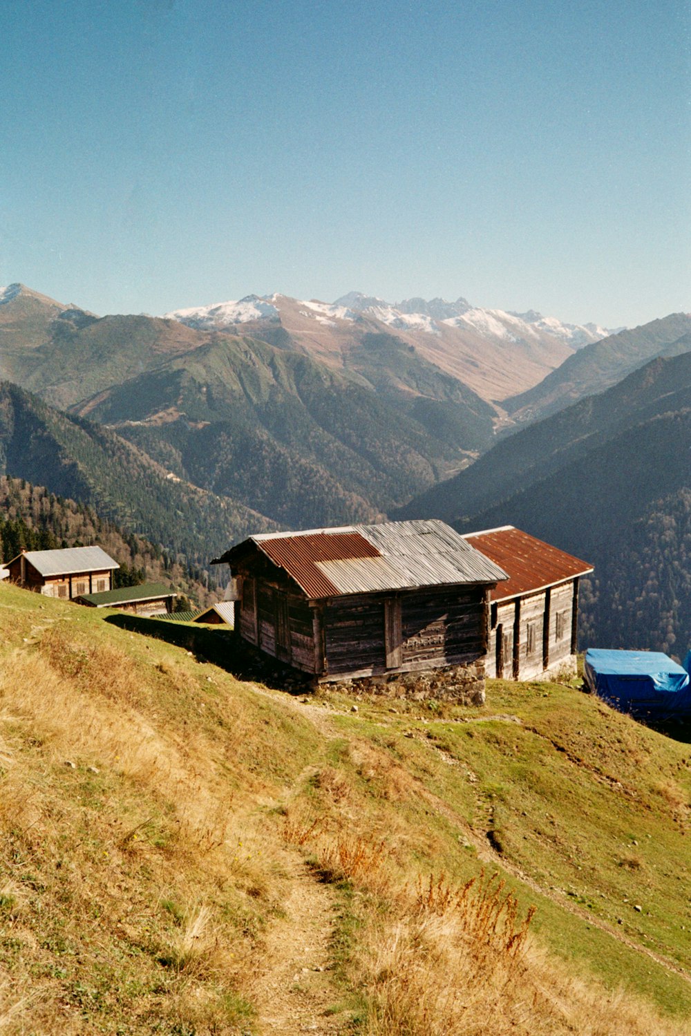 uma casa em uma colina com montanhas ao fundo