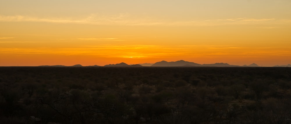 the sun is setting over the mountains in the desert