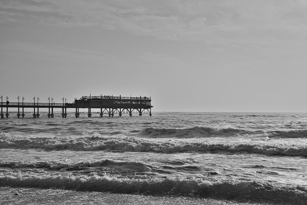 a black and white photo of a pier in the ocean