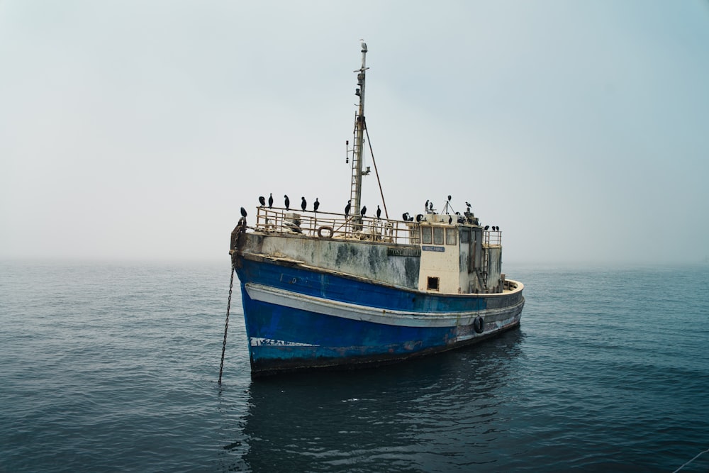 a blue and white boat in the middle of the ocean