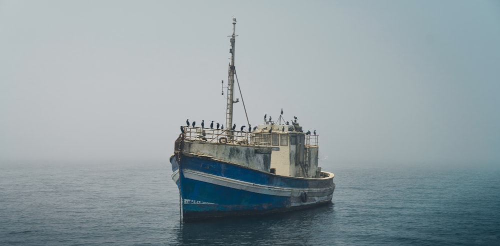 a blue and white boat in the middle of the ocean