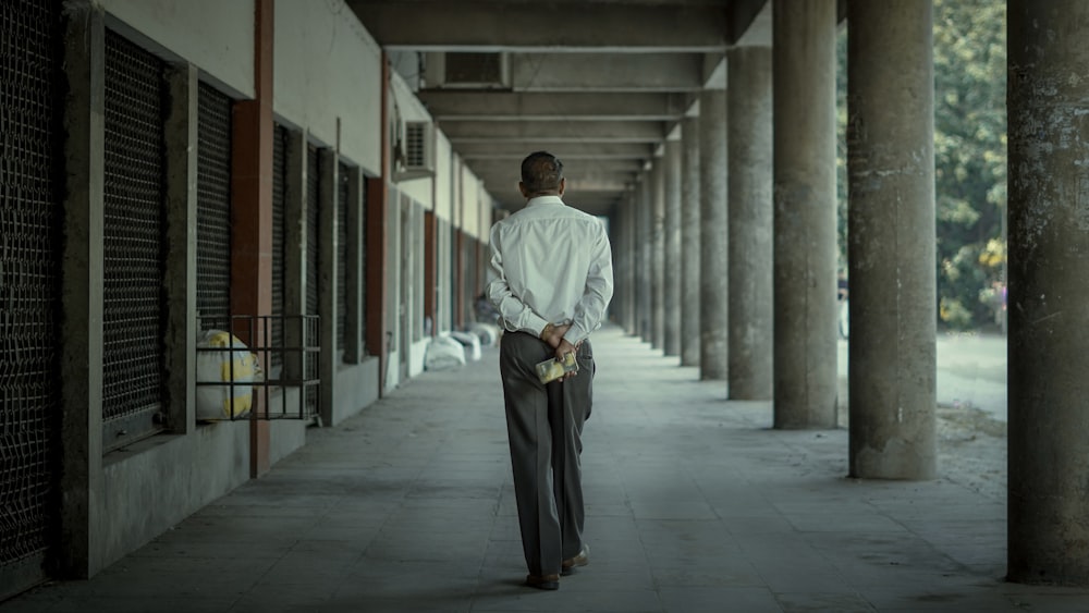 a man in a white shirt is walking down a hallway