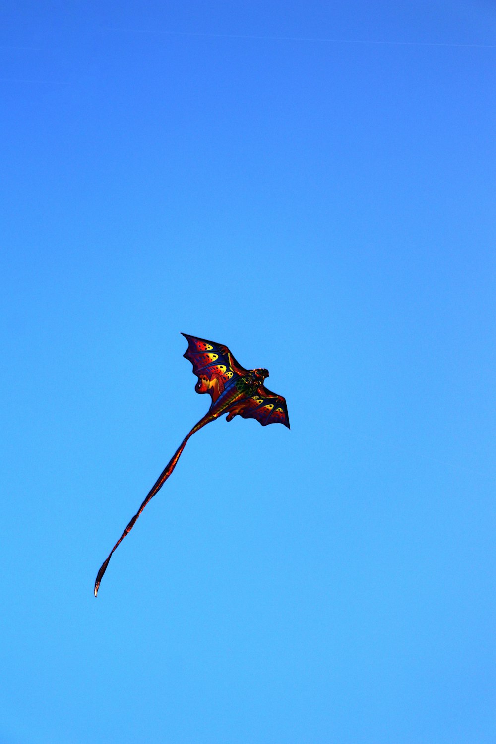 a colorful kite flying in a blue sky