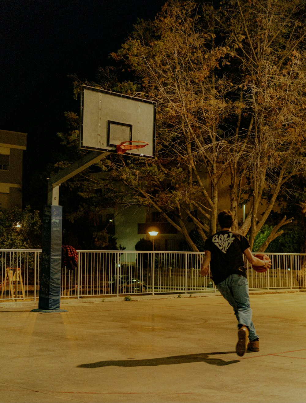 Um jovem está jogando basquete em uma quadra