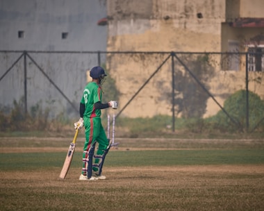 a person in a green uniform holding a baseball bat